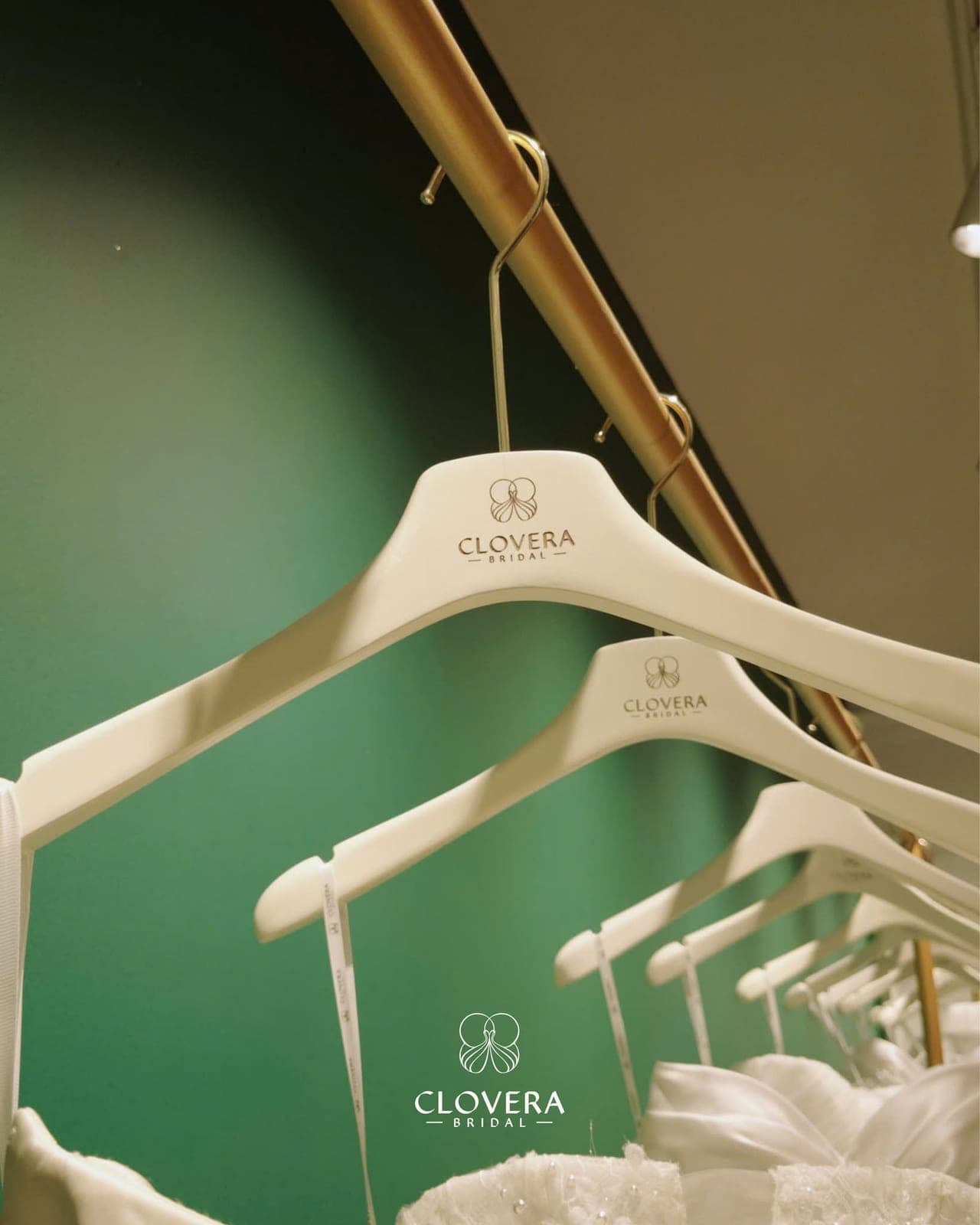 Clovera Bridal branded hangers on a gold rail